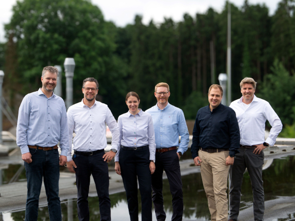 Eine Gruppe von sieben Männern steht auf einem Flachdach
